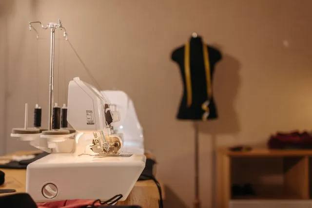 Dikiş makinesi ve bulanık arka planda bir terzi mankeni, atölye çalışma masası