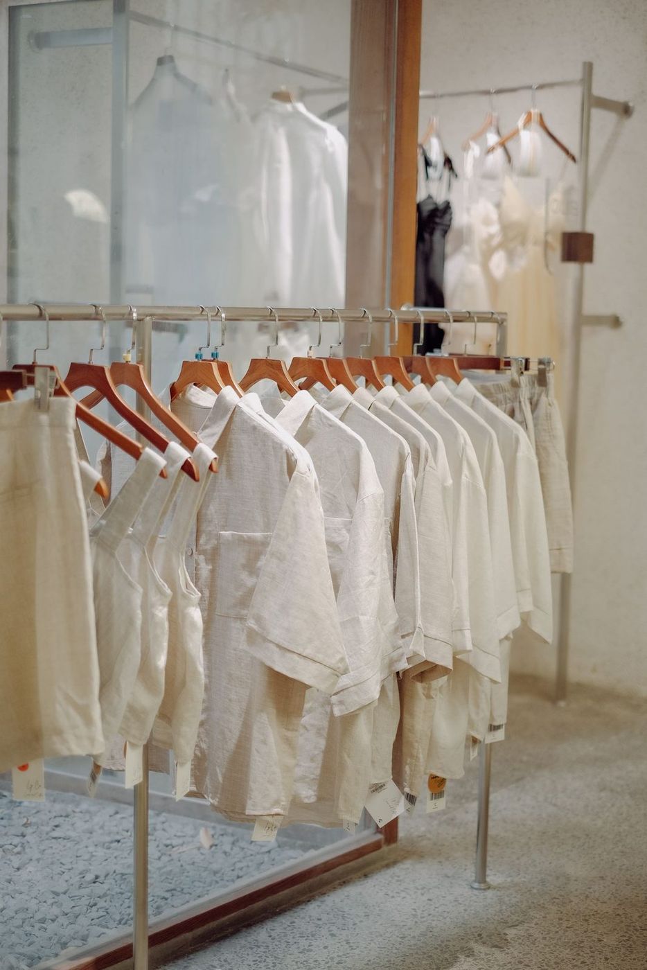 Butik içinde ahşap askılarda sıralanmış krem ve beyaz parçalar